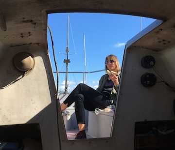 woman eating egg salad sandwich aboard
                      moored sailboat, leschi marina south moorage